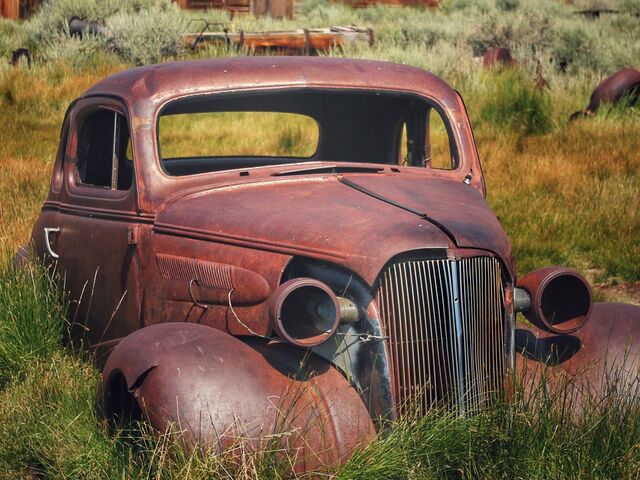 rusted out car in a field